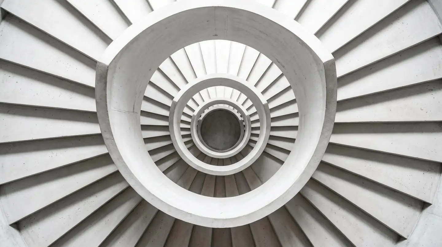 Escalier en colimaçon blanc vu d'en haut, spirale géométrique avec ombres rythmées et lumière zénithale